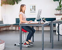 Kvinde der sidder på en ergonomisk stol på arbejdspladsen